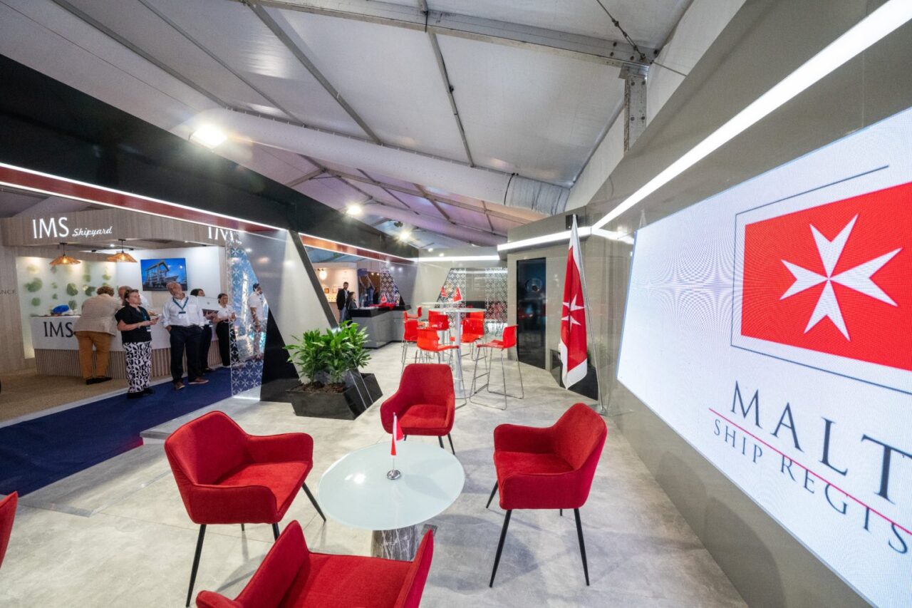 The Malta Ship Registry stand at the Monaco Yacht Show, with red chairs, Maltese flags and a large Malta Ship Registry screen